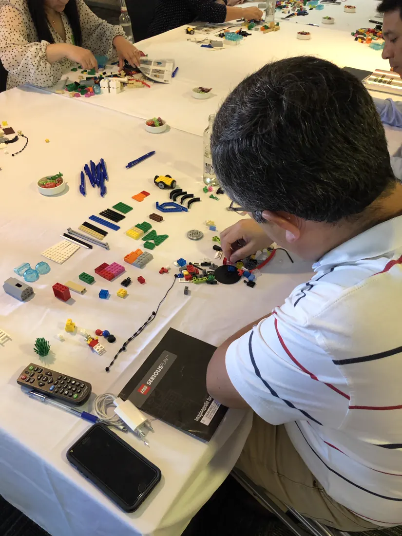 Participante construye un modelo con piezas LEGO en una mesa de taller