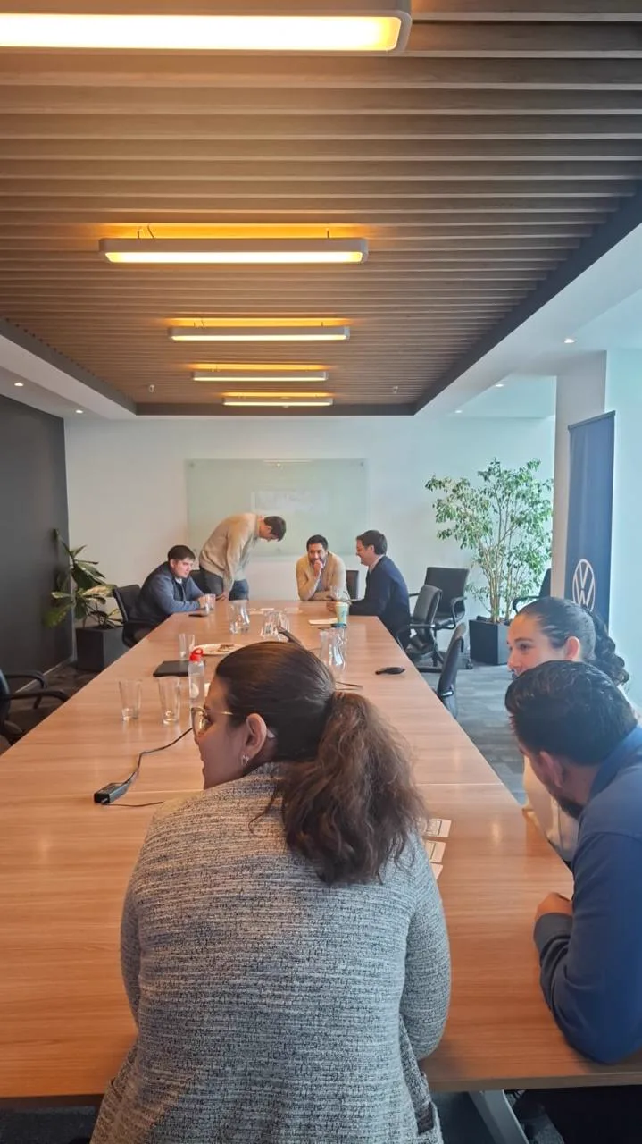 Participantes trabajan en grupos alrededor de una mesa larga